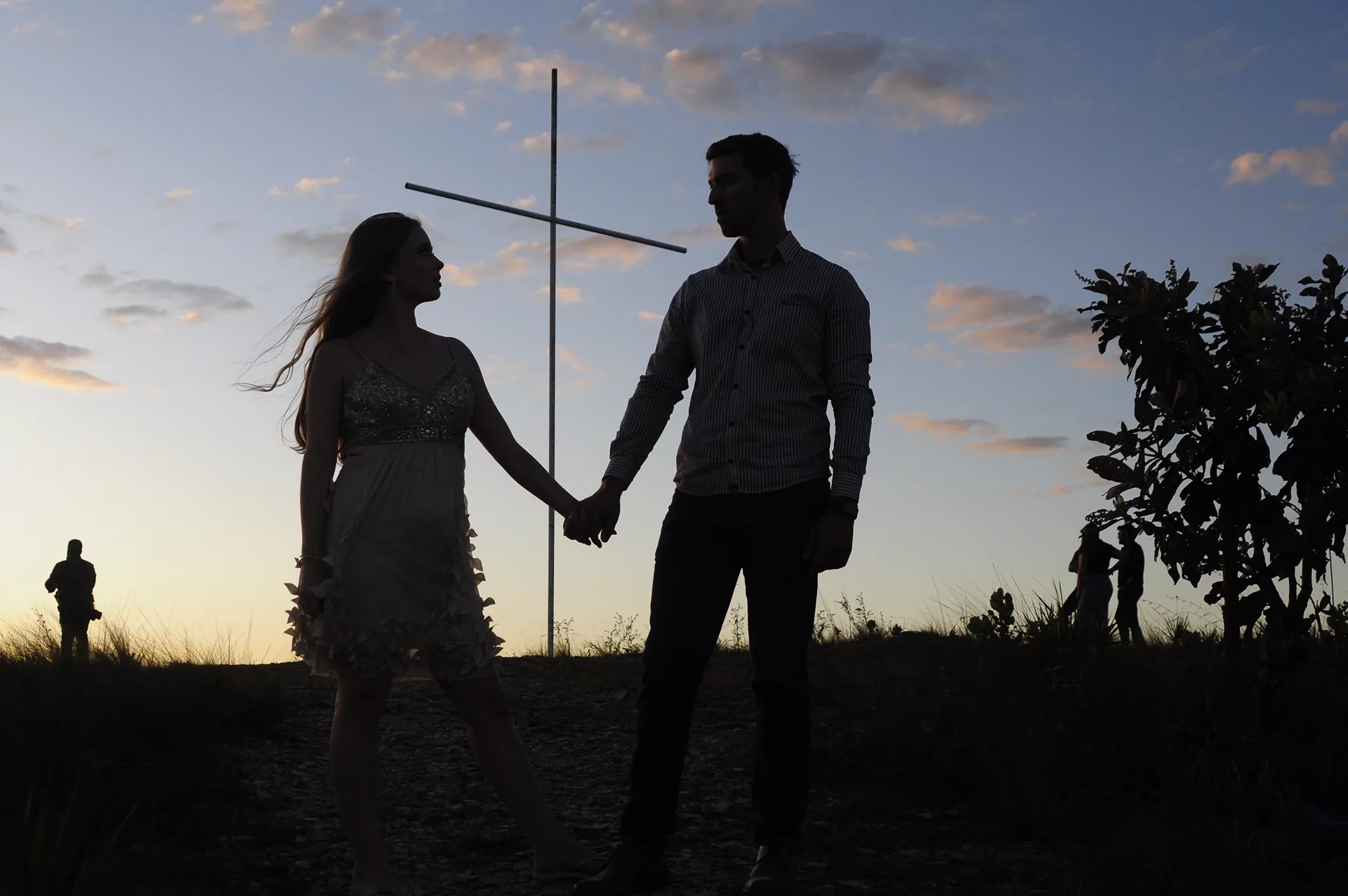 Casal de mãos dadas em silhueta sob o céu do entardecer