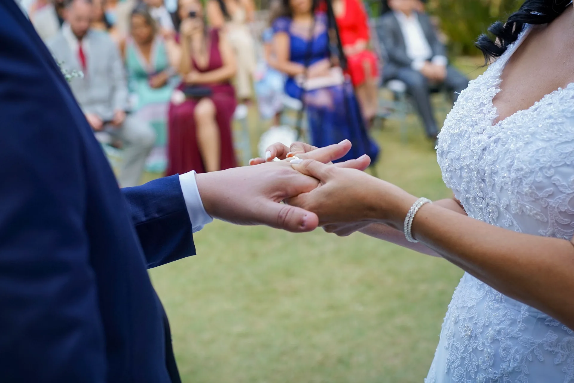 Detalhe das mãos do casal durante a troca de alianças
